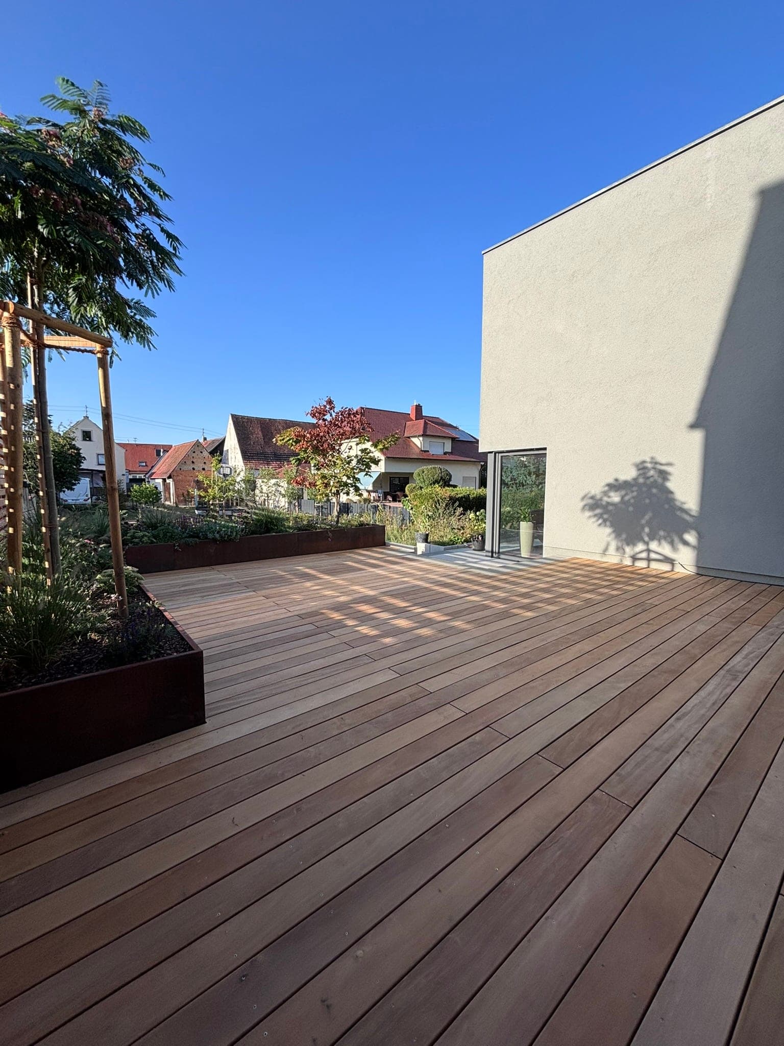 Holzterrasse mit Hochbeet und Baum