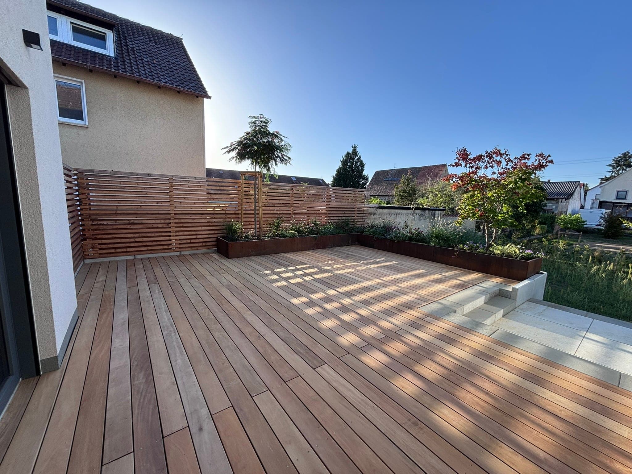 Große Holzterrasse mit Stufen zum Garten