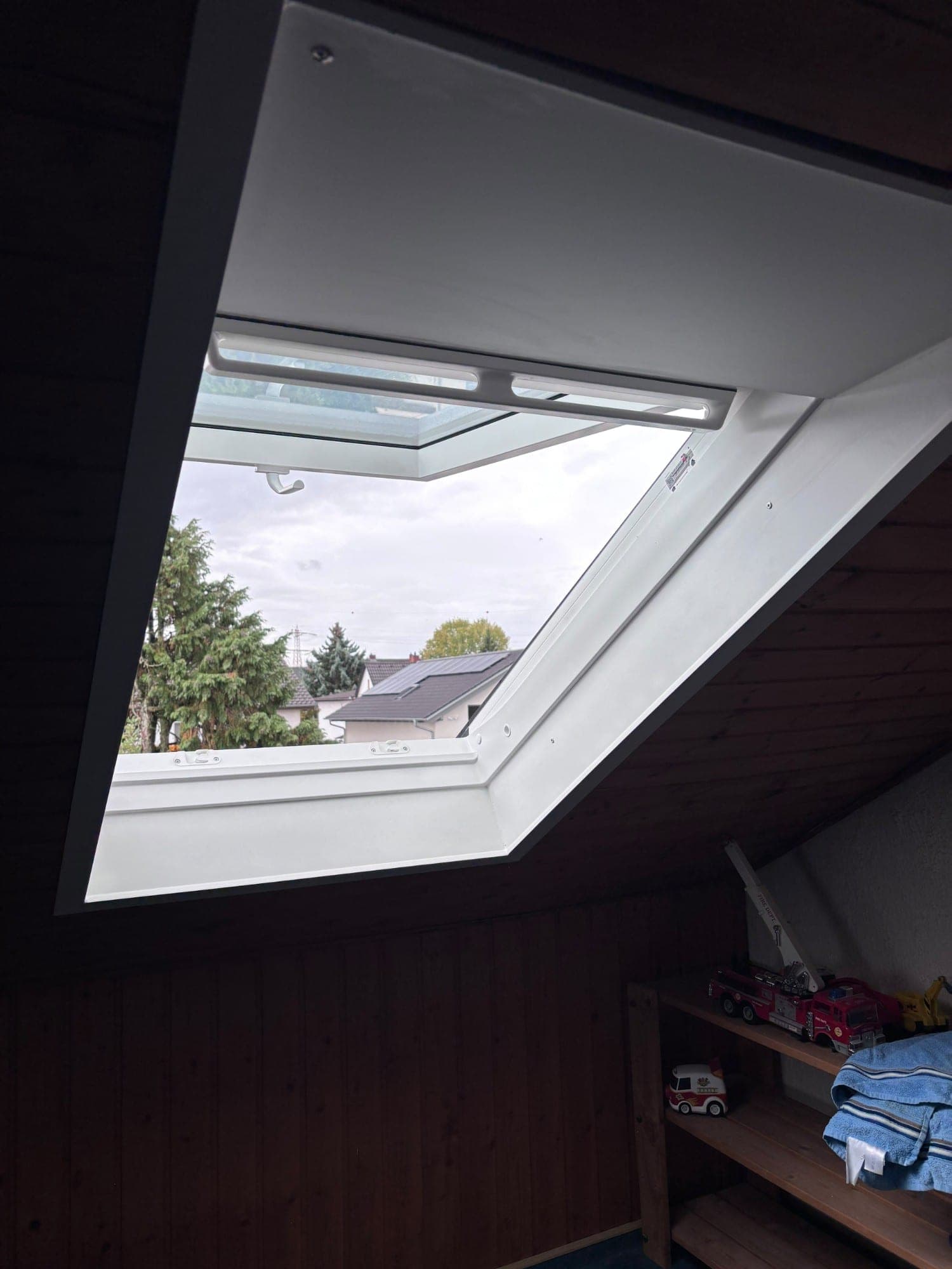 Geöffnetes Dachfenster mit sauber verkleideter Laibung und Blick auf die Dächer