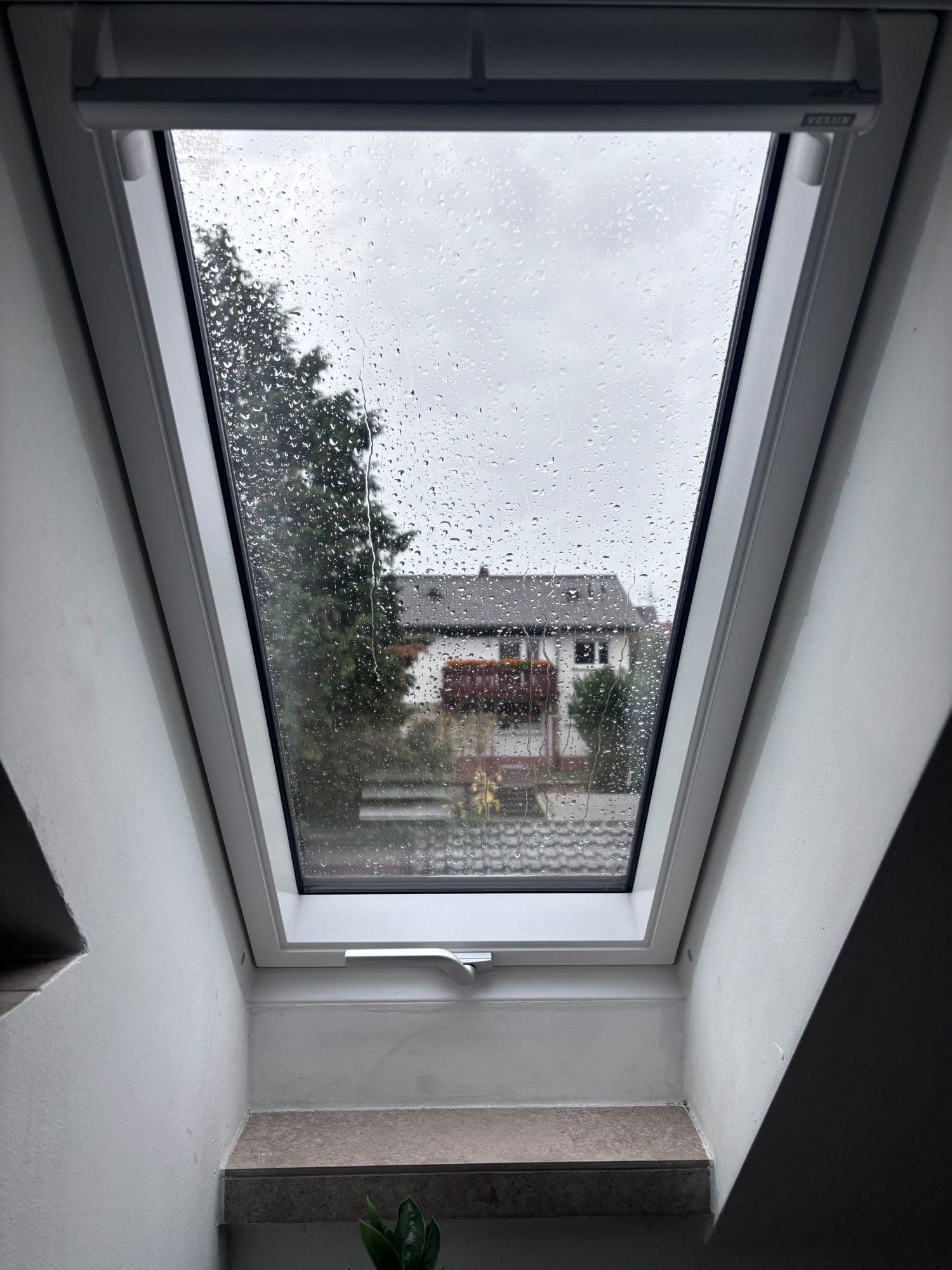 Neues Dachfenster mit Blick auf die Nachbarhäuser, Regentropfen auf der Scheibe